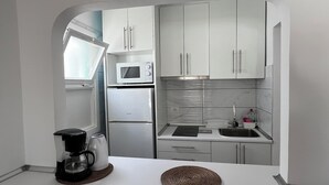 A compact kitchen with white cabinets, a microwave, a refrigerator, and a coffee maker.