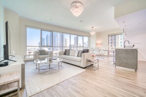 A modern living room with a large window, a sofa, a coffee table, and a chandelier.