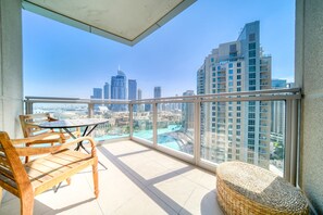 A balcony with a view of a cityscape, including tall buildings and a body of water.