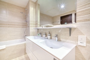 A modern bathroom with two sinks, a shower, and a vanity with storage.
