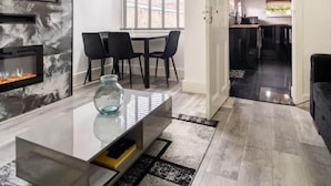 A modern living room with a fireplace, a dining area, and a view of the kitchen. - House With Modern Interior, Conveniently Located (Manchester)
