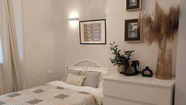 Un dormitorio con cama, mesitas de noche, cómoda y un cuadro colgado en la pared.