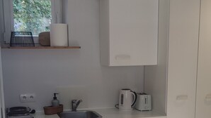 Una cocina moderna con armarios blancos, encimera de madera y ventana con vistas a zonas verdes.