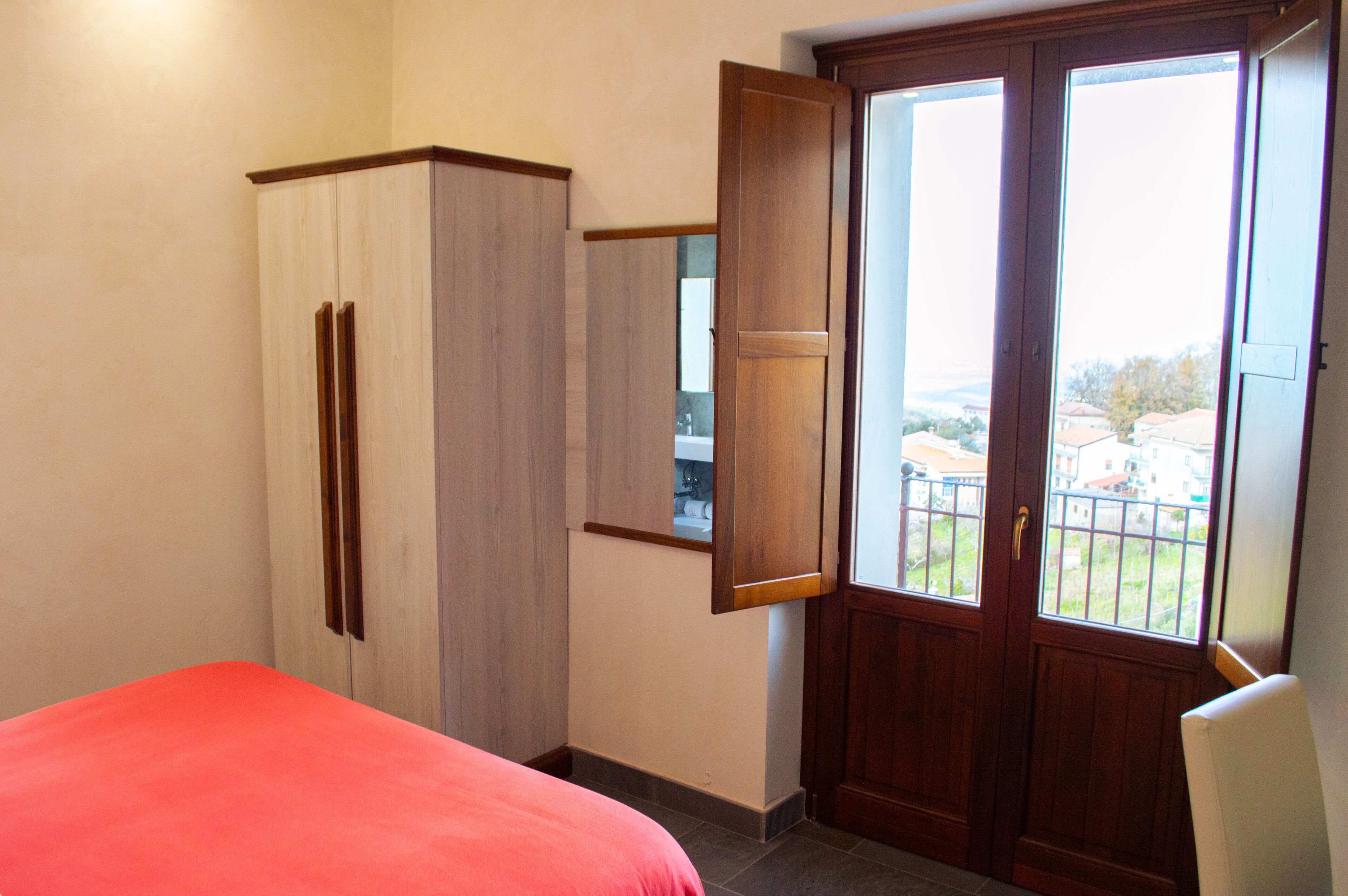 Un dormitorio con cama, armario y puerta que da a un balcón.