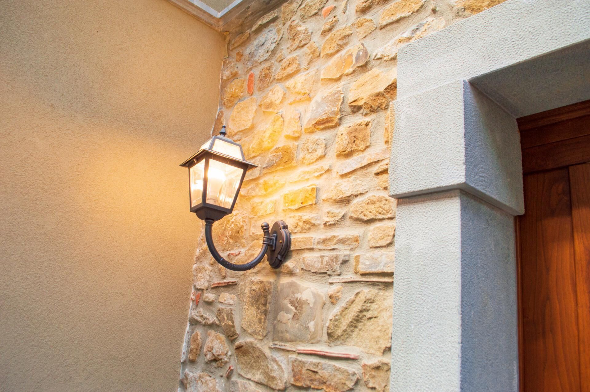 A stone wall with a wall-mounted lantern and a wooden door.