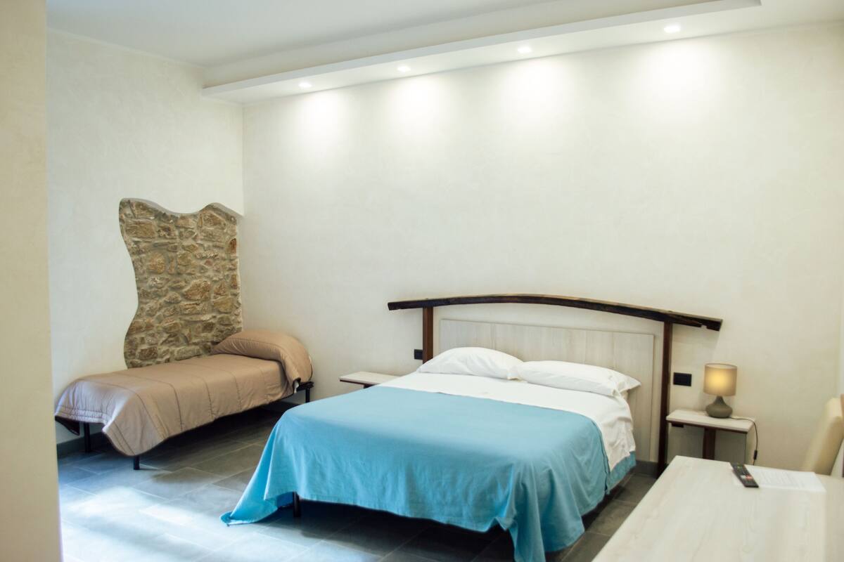 Ein Hotelzimmer mit Bett, Sitzbank, Nachttisch und Lampe.