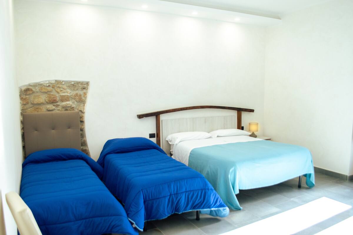 Ein Hotelzimmer mit zwei Einzelbetten, einer Wand aus Stein und einem hölzernen Kopfteil.