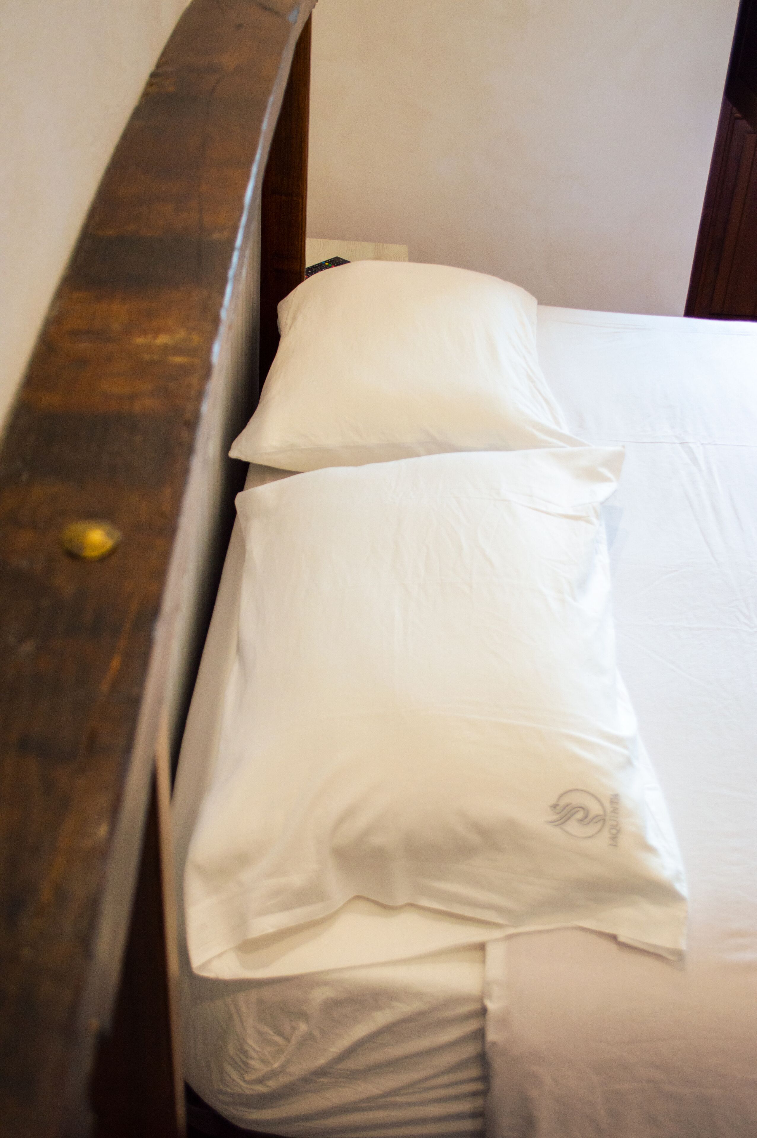 A bed with white bedding and a wooden headboard.
