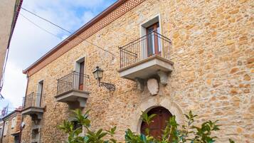A stone building with balconies, a wooden door, and a wrought iron balcony railing.