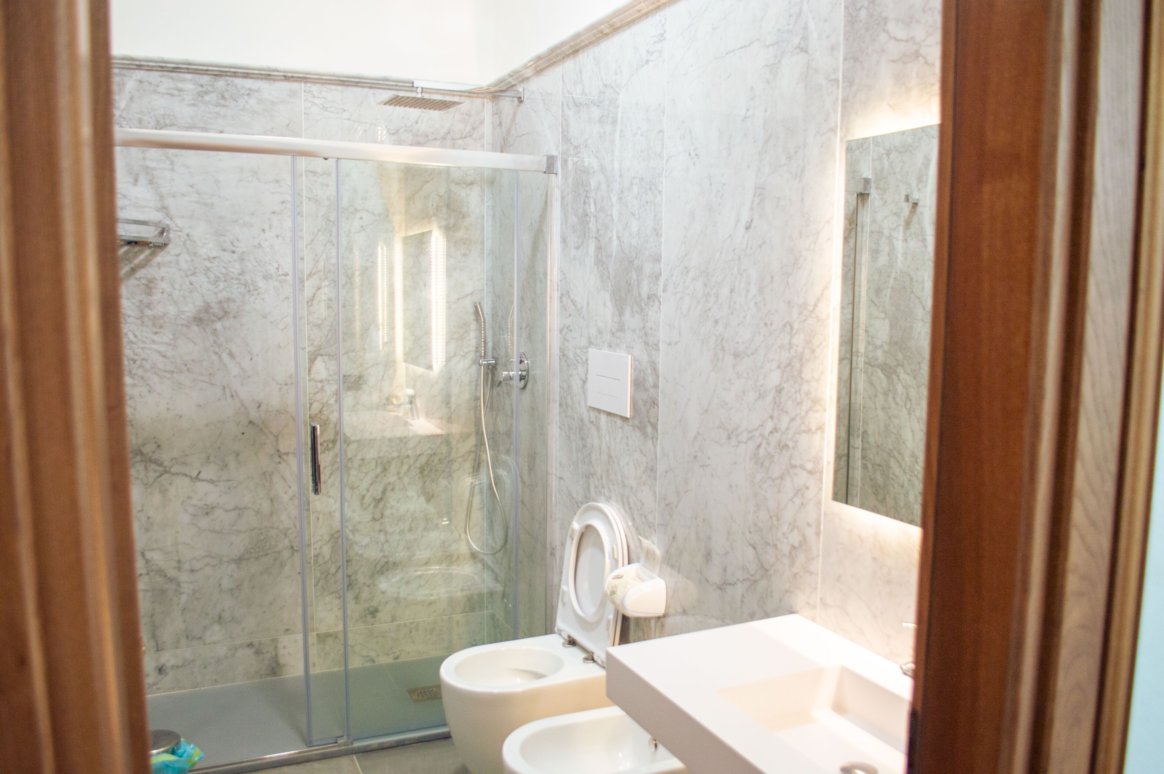 Une salle de bain avec une douche à parois de verre, des toilettes et un lavabo avec un miroir.