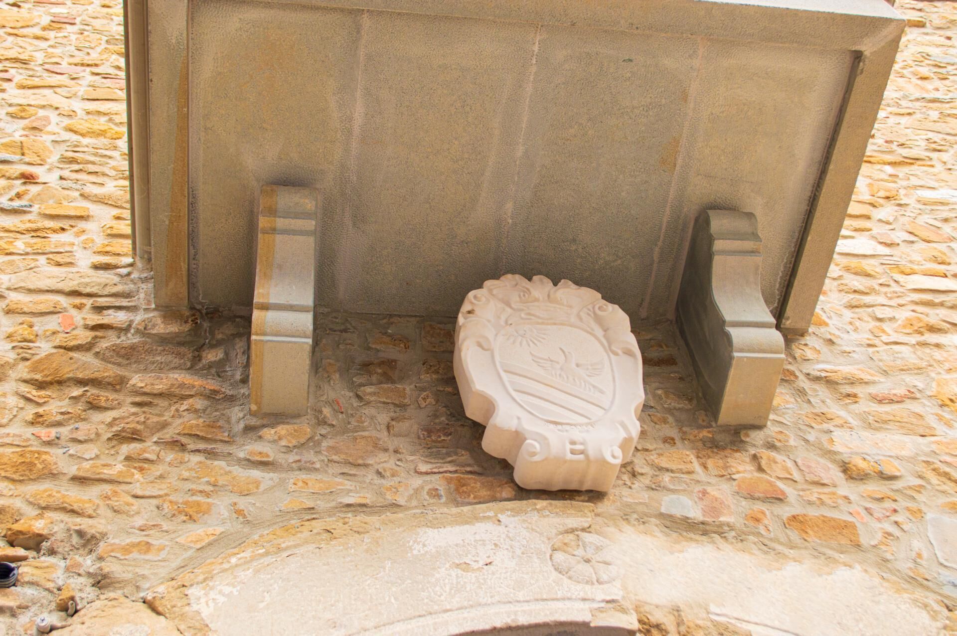 A stone bench with an engraved emblem, set on a cobblestone surface.