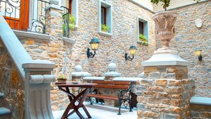 A stone courtyard with a wooden bench and tables, stone walls, and decorative lanterns. - Palazzo Iaquinta - Rooms & Restaurant (Cicerale)