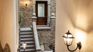 A stone staircase leading to a wooden door with a glass panel, flanked by two wall-mounted lanterns. - Palazzo Iaquinta - Rooms & Restaurant (Cicerale)