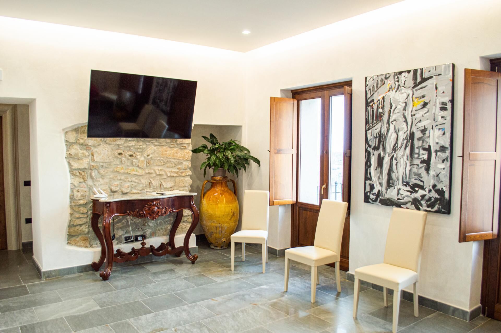 A modern interior with a stone wall, a large vase, and two chairs.