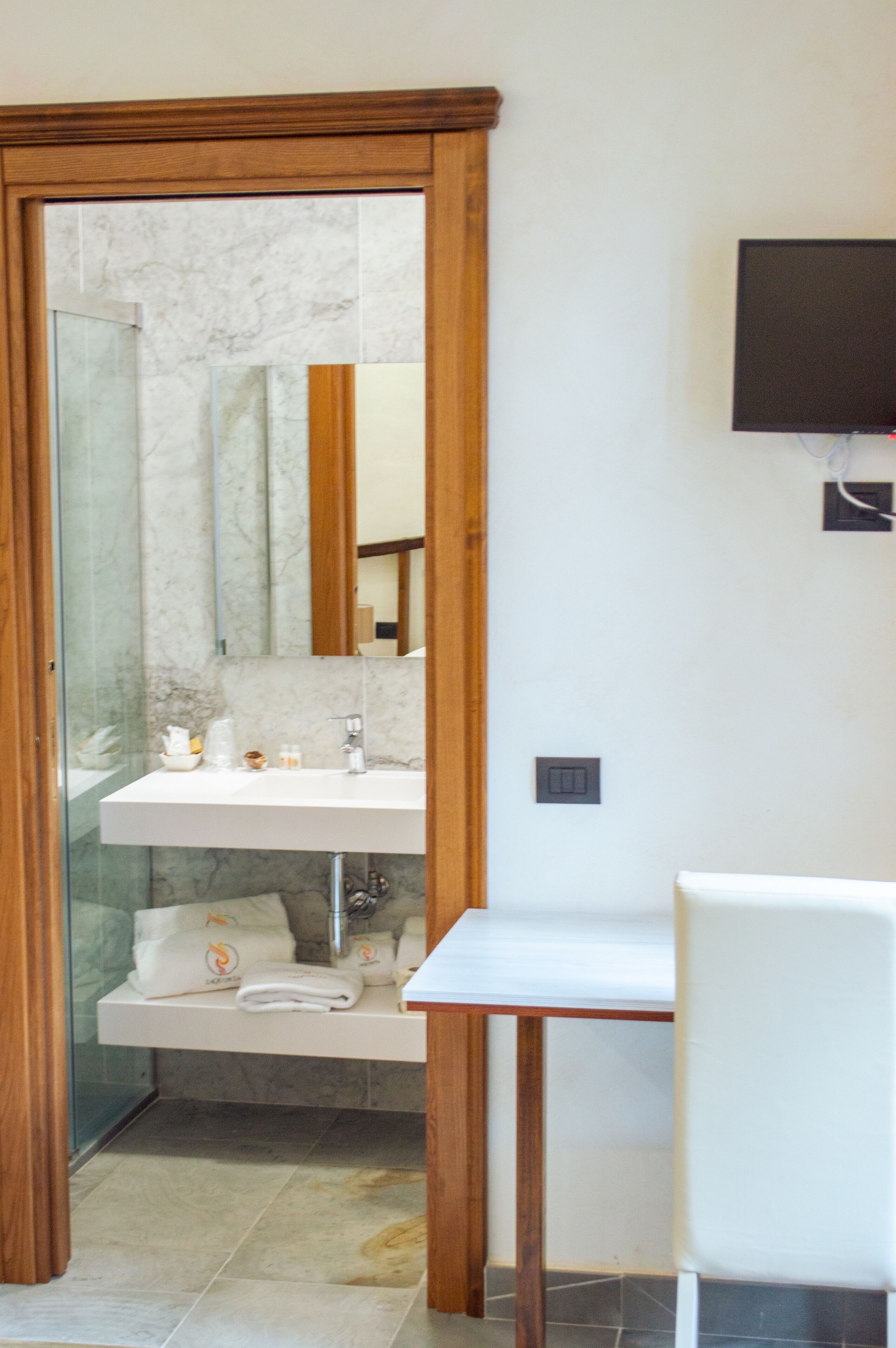 A bathroom with a glass shower door, a white sink, and a wooden vanity.