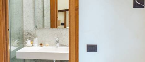 A bathroom with a glass shower door, a white sink, and a wooden vanity.