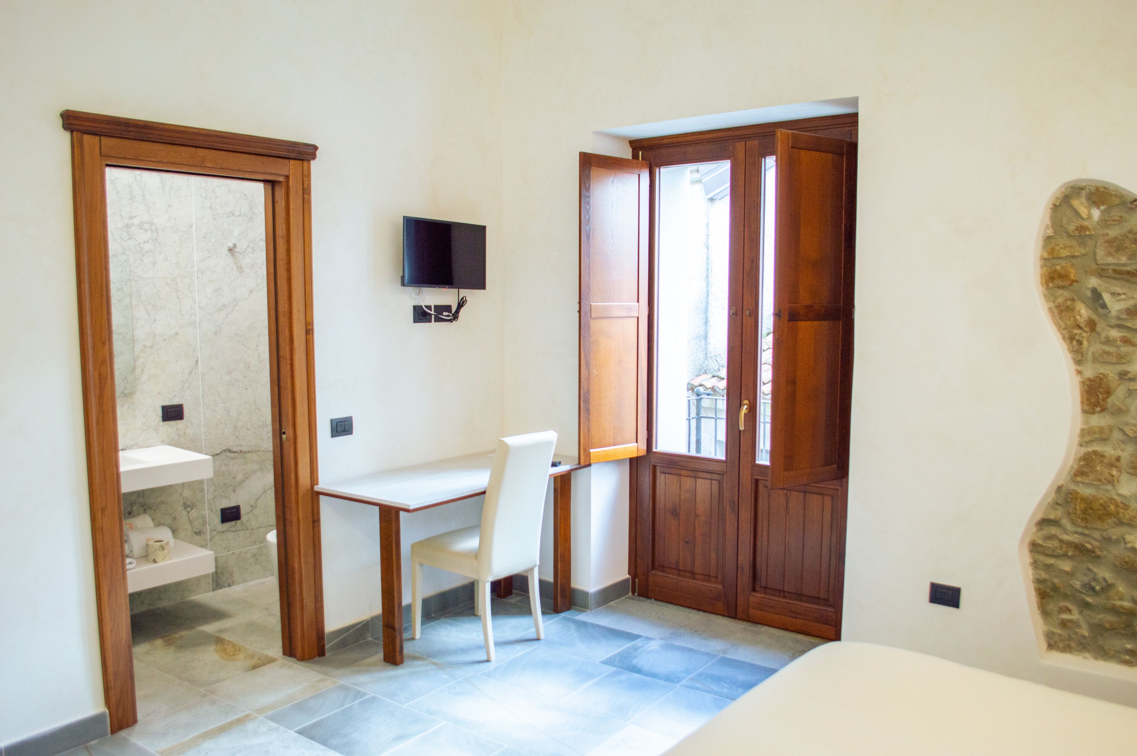 A small room with a desk, chair, and a television mounted on the wall.