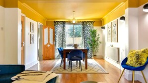 A dining area with a wooden table and chairs, a potted plant, and a blue chair with a fur throw. - House - Sleeps up to 9 & Free Parking (Cardiff)