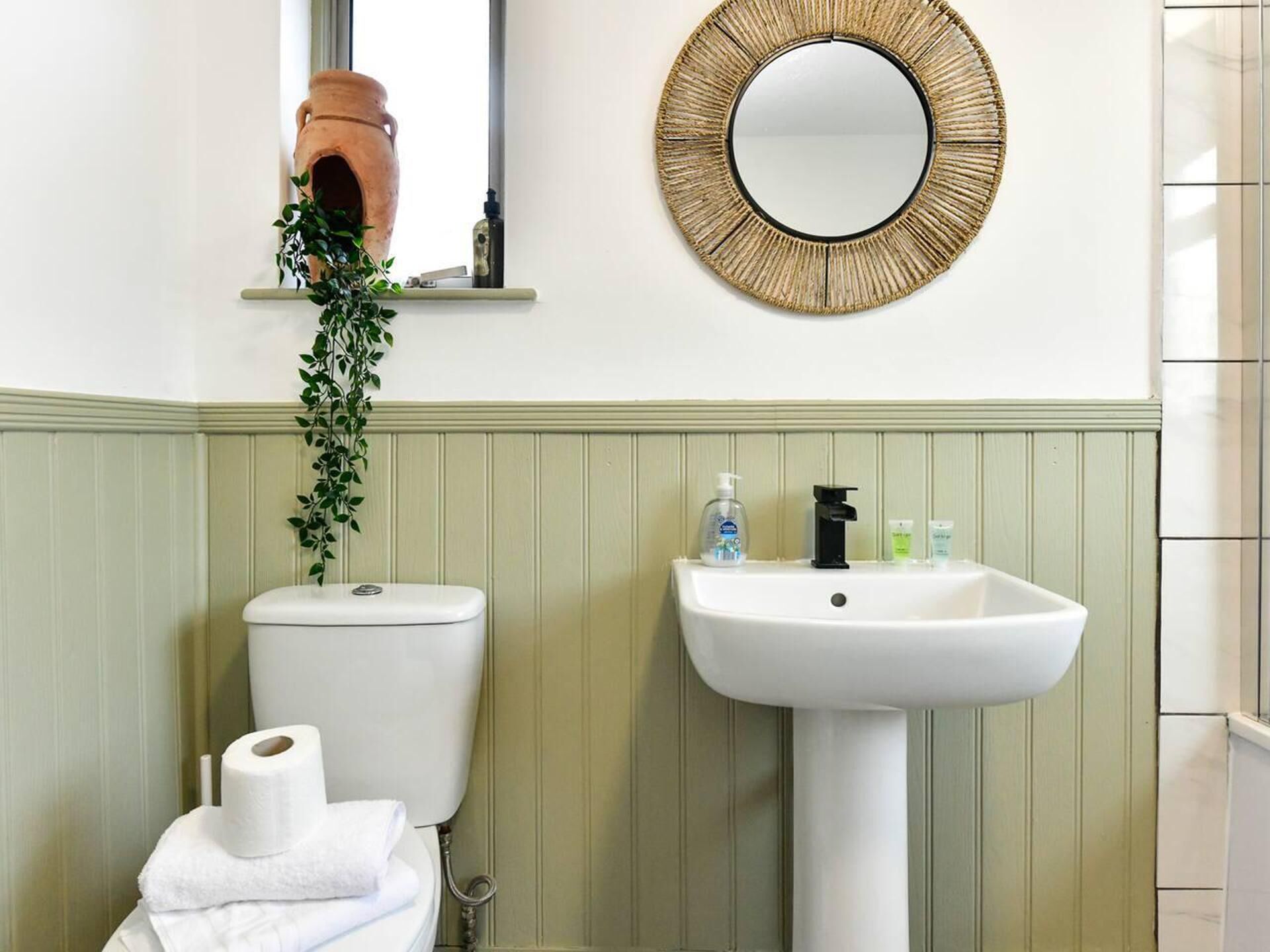 A bathroom with a toilet, sink, and a mirror.