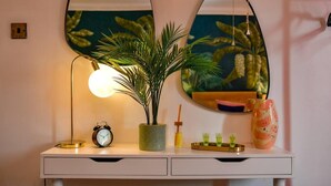 A white desk with a lamp, a potted plant, a mirror, an alarm clock, and a tray with small containers. - House - Sleeps up to 9 & Free Parking (Cardiff)