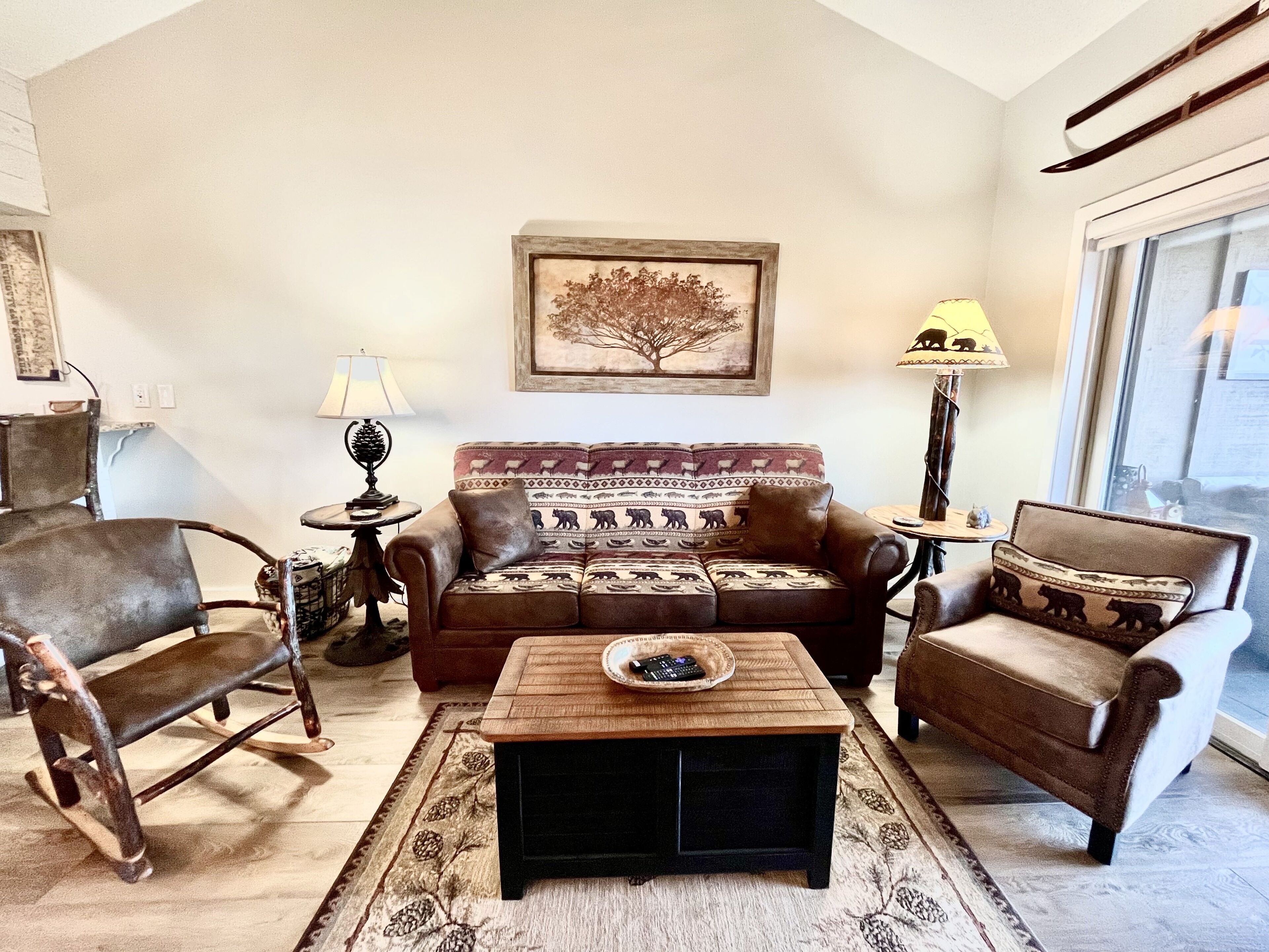 A living room with a brown sofa, a wooden coffee table, and a patterned rug.