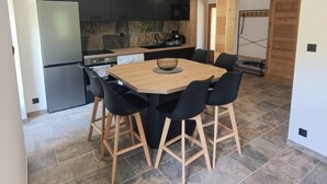 Una cocina moderna con armarios oscuros, una mesa de comedor de madera y sillas negras.