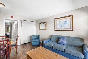 A living room with a blue sofa, a wooden coffee table, and a blue armchair.