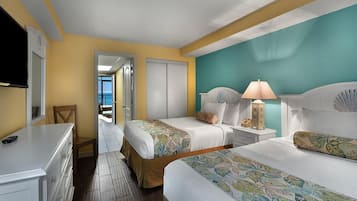 A hotel room with two beds, a TV, a dresser, and a view of the outside.