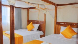 Une chambre avec deux lits, chacun étant agrémenté de draps blancs et d’un élément décoratif jaune.