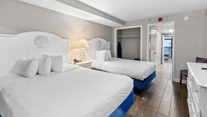 Une chambre d’hôtel avec deux lits, une armoire et un bureau.