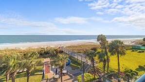 Une propriété située en bord de mer, dotée d’un patio, de palmiers et offrant une vue sur l’océan.
