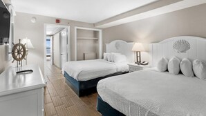 Une chambre d’hôtel avec deux lits, un bureau et un dressing.