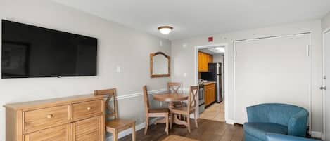 A compact living space with a dining area, a kitchen in the background, and a blue armchair.