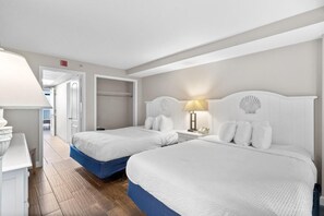 Two single beds with white bedding and blue headboards, each with a bedside table and lamp.