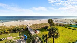 A beach view with a playground, palm trees, and a sandy beach. - Roomy Oceanfront Ste with Free Breakfast 4th Flr (Myrtle Beach)