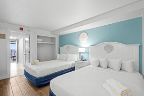 A hotel room with two beds, a bathroom, and a view of the outside.