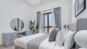 A modern bedroom with a bed, a dresser, a mirror, and a window with curtains. - Vogue | Rahaal Madinat Jumeirah near Burj Al Arab (Dubai)