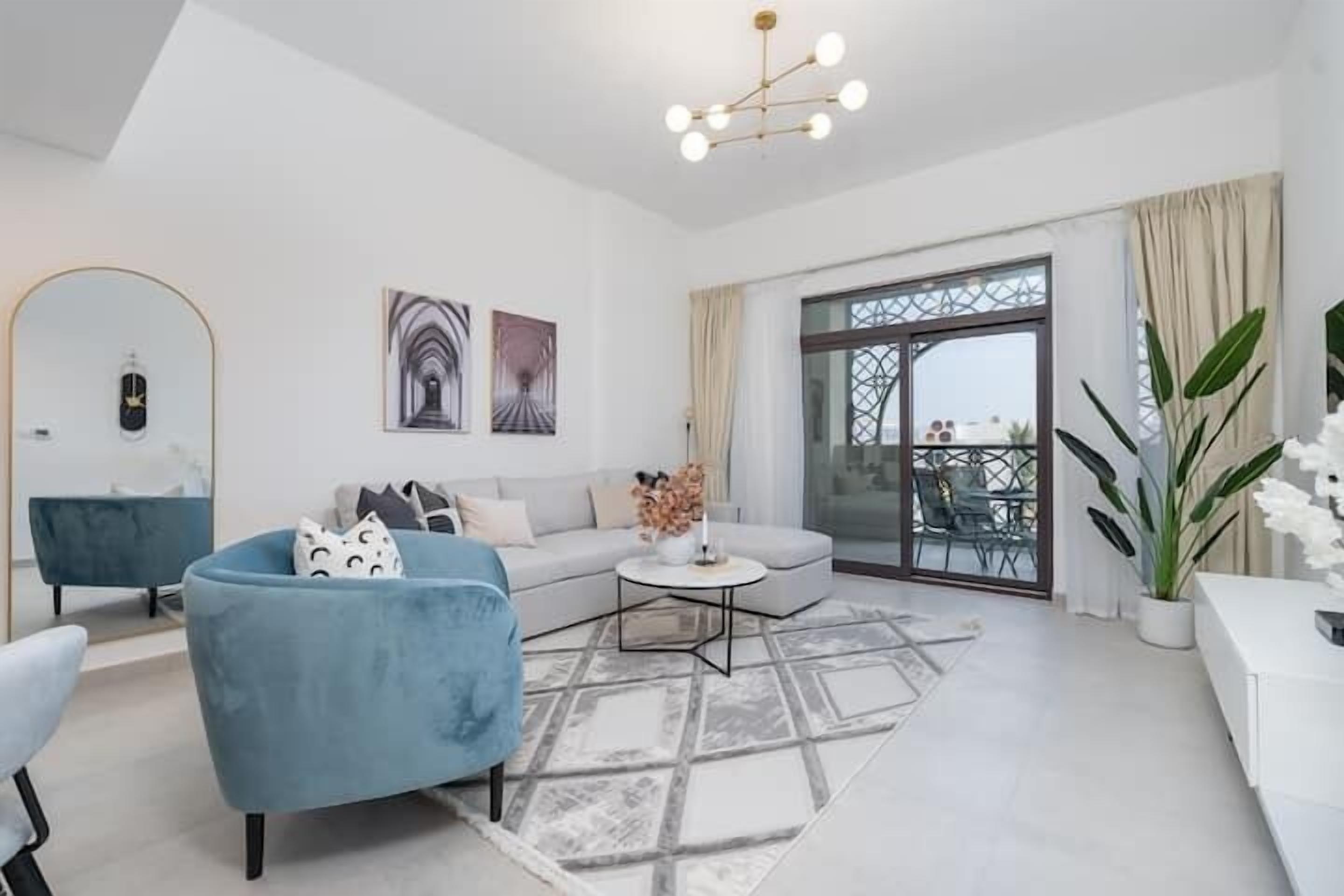 Un salon moderne comprenant un canapé, un fauteuil et une table basse, une grande fenêtre offrant une belle vue et un lustre.