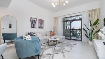 Un salon moderne comprenant un canapé, un fauteuil et une table basse, une grande fenêtre offrant une belle vue et un lustre.