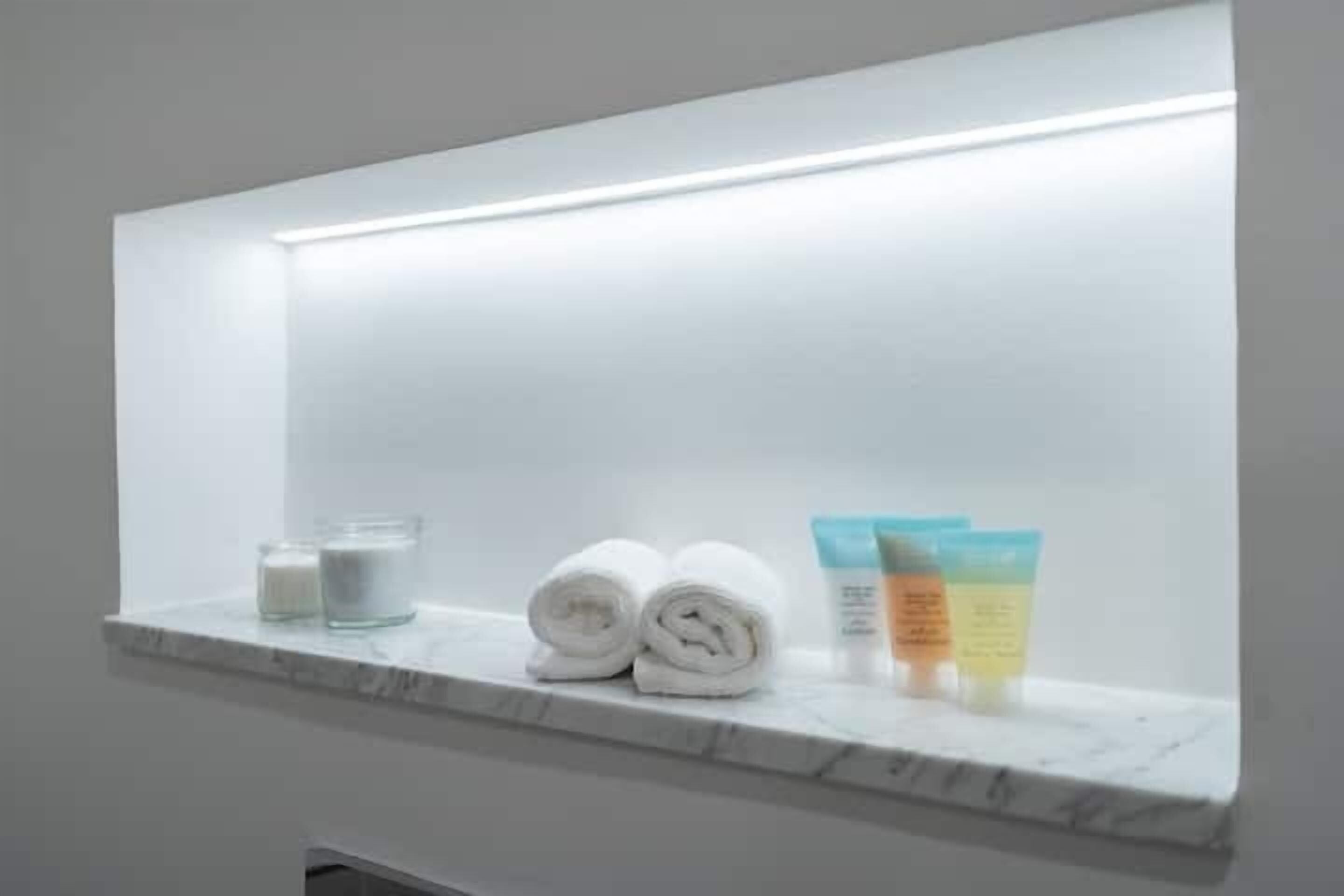 Ein Badezimmer mit Marmorplatte, zwei gerollten Handtüchern, zwei Glasbehältern und drei Toilettenartikeln.