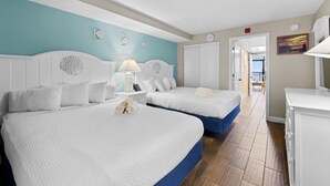 A hotel room with two beds, a bathroom, and a view of the outside.