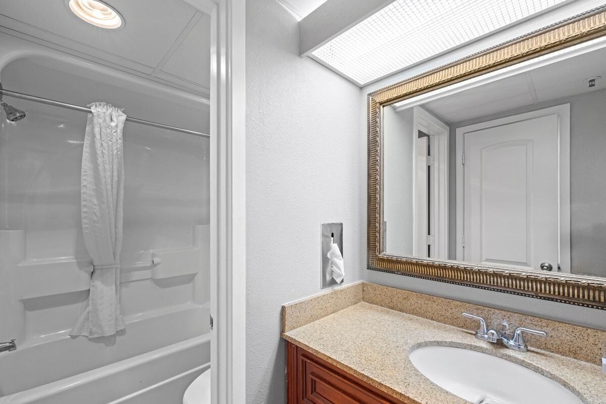 A bathroom with a shower, a sink, and a large mirror.