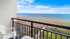 Een balkon met uitzicht op een strand en de oceaan.