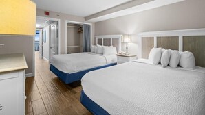 Een hotelkamer met twee bedden, een kledingkast, een nachtkastje en een lamp.