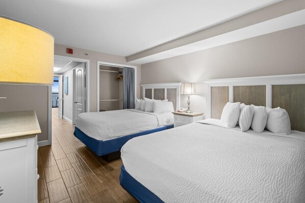 Ein Hotelzimmer mit zwei Betten, einem Kleiderschrank, einem Nachttisch und einer Lampe.