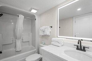 Een moderne badkamer met bad, toilet en wastafel.