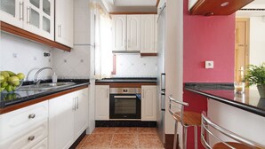 Eine Küche mit weißen Schränken, einer schwarzen Arbeitsplatte, einer roten Wand und einem Edelstahlbackofen.