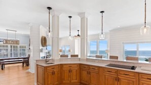 Une cuisine spacieuse avec des meubles en bois, un grand îlot central et des luminaires suspendus.