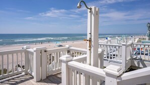 Une vue sur la plage depuis un balcon doté de balustrades blanches, avec la mer et la plage en contrebas.