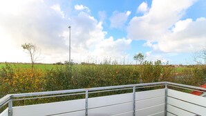 A metal railing overlooking a green field with a clear sky. - Ferienwohnung Seebeere- Obergeschosswohnung in Norddeich für bis zu 4 Personen (Norden)